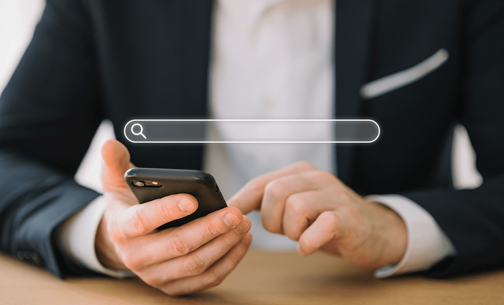 Busca. Imagem das mãos de um homem mexendo no celular. Na parte de cima aparece o campo de busca do Google.