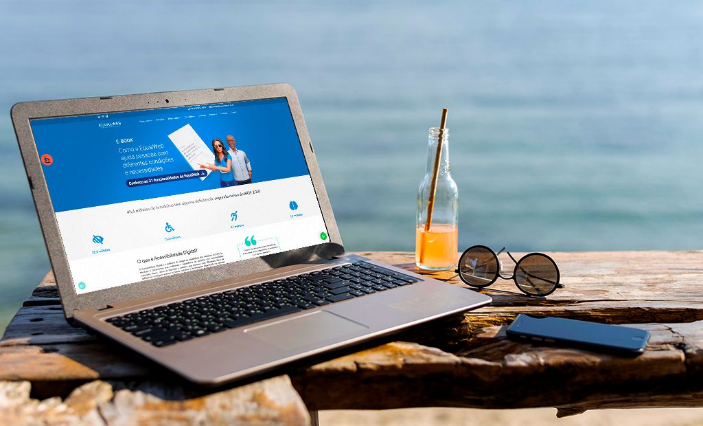 Turismo. Imagem de um notebook aberto na página da equalweb e o notebook está na beira da praia.